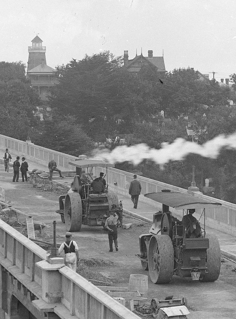 A crop of an atmospheric view of the construction of Grafton Bridge, Auckland, with Partington's mill in its observation tower phase.